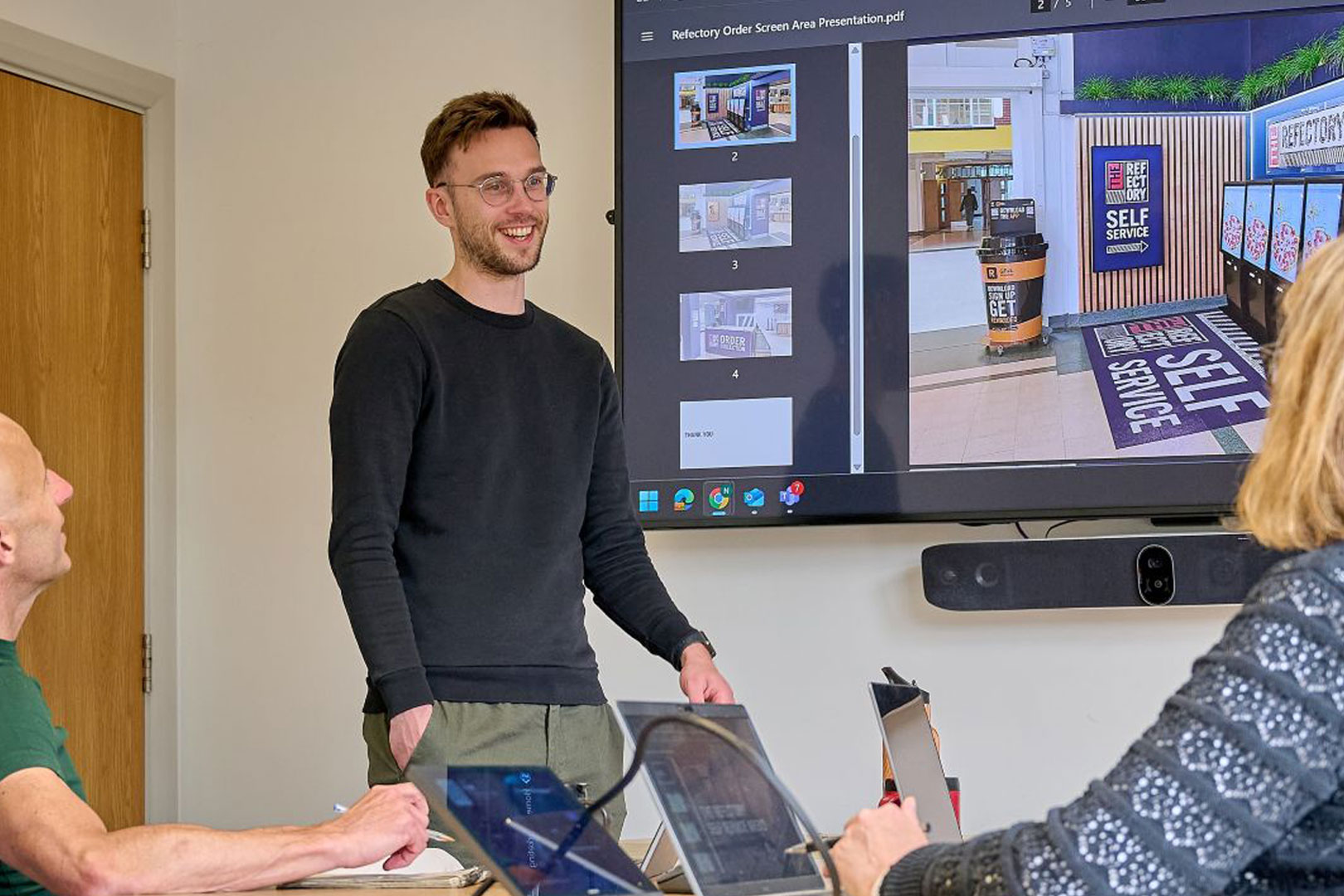Marketing team member delivering a presentation with a screen behind them.